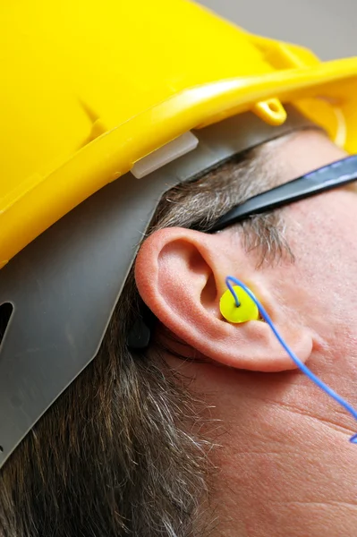 Κίτρινο earplug στο αυτί κοντινό πλάνο Φωτογραφία Αρχείου