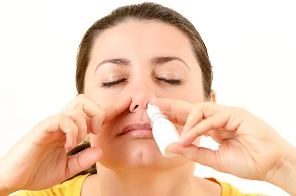 Mujer usando spray nasal Imágenes de stock libres de derechos