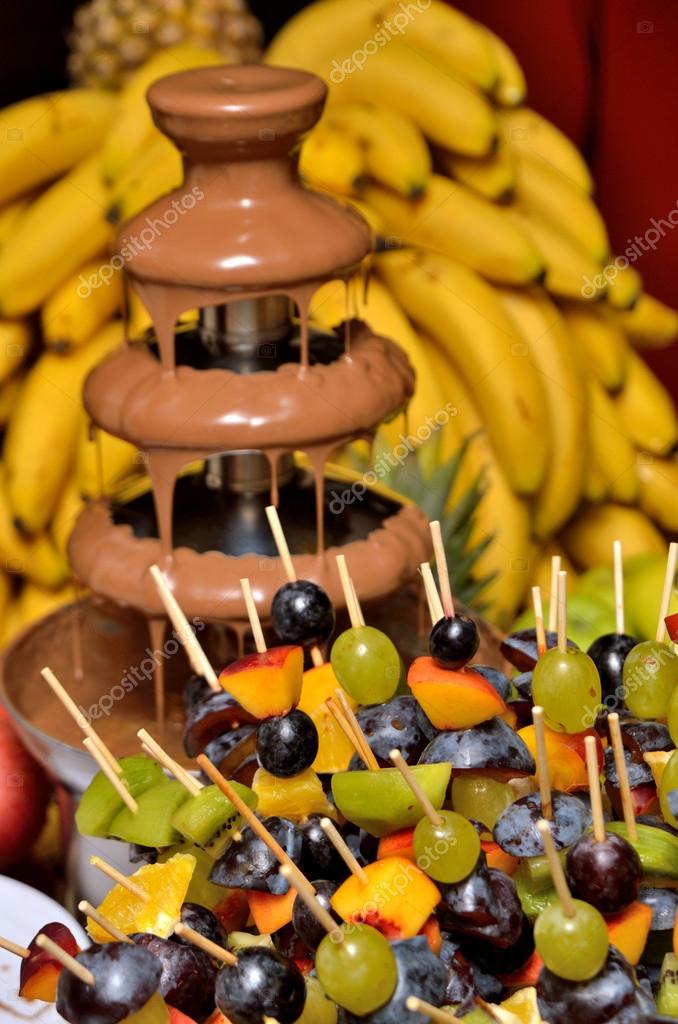 Dipping fruits into a Chocolate Fountain — Stock Photo © florinoprea1