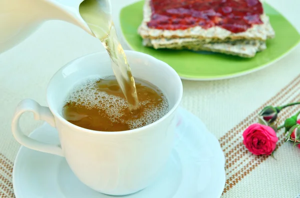 Verser le thé dans une tasse avec du pain croustillant et de la gelée — Photo