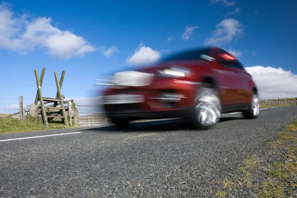 Red car speeding on empty mountain road — Stock Photo, Image