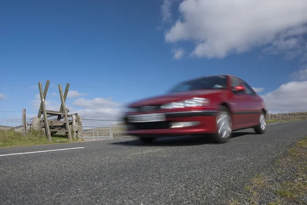 Red car speeding on mountain road in Devon — Stock Photo, Image
