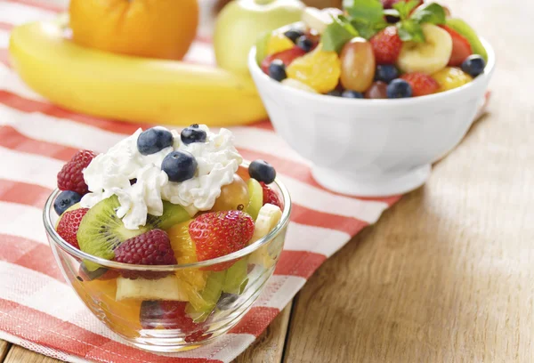 Ensalada de frutas sabrosas dulces en el tazón con crema batida —  Fotos de Stock