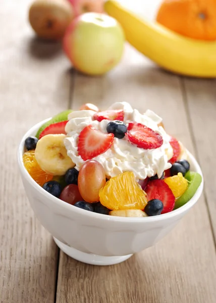 Sweet tasty fruit salad in the bowl with whipped cream — Stock Photo, Image