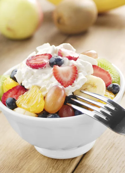 Sweet tasty fruit salad in the bowl with whipped cream — Stock Photo, Image