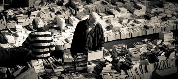 Oude man op zoek via boeken — Stockfoto