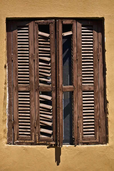 Achient braunes Fenster an einem senfgelben Haus in sarti, Griechenland — Stockfoto