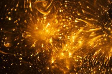 Altın sarısı ışıkları olan soyut ve şenlikli bir arka plan. Odaklanmış bulanık ışıklar.