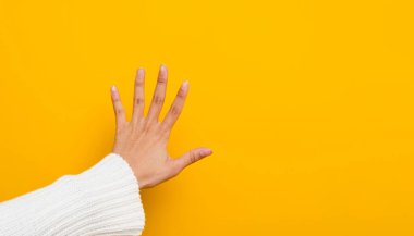 female hand making a prohibition and stop sign lonely on a yellow background