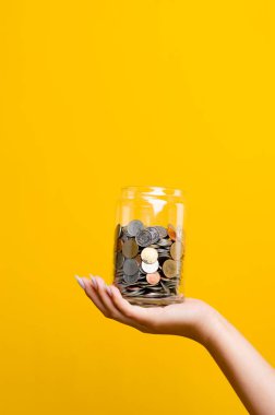 El ve para, madeni para, para, tasarruf para bankacılık ve mali işler için kullanılan para sarı bir arka planda cam bir kavanoz içinde para