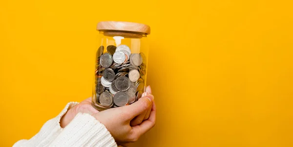 Para biriktiriyorum. Genç bir kadının eli bardakta bozuk para tutuyor. Finansal muhasebe için para tasarrufu kavramı.