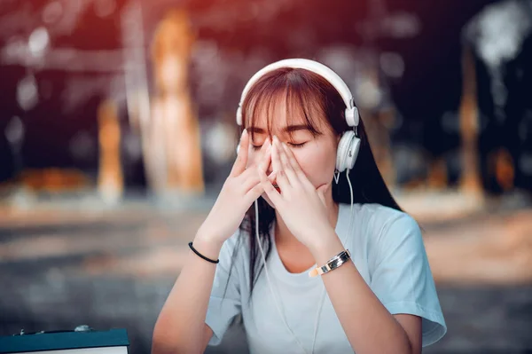 Müzik dinliyordum. Kulaklıklı güzel bir kadın masasında dinleniyor. Gözlerini kapat ve meditasyon yap, meditasyon yap. Akıllı telefonu, rahatlama ve rahatlama konseptini kullanarak müzik dinliyor..