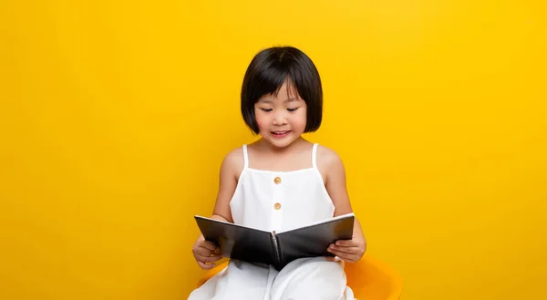 asian girl Sit and read a book and smile happily. Self-reading concept in childhood. Smart kid. Creative kid. Smart kid.