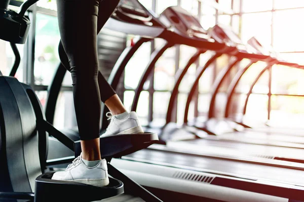 Spor salonundaki Asyalı kız otomatik koşu bandında egzersiz yapıyor.