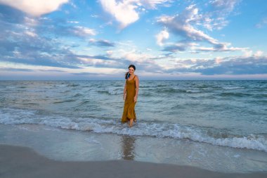 Çekici, çekici genç bir kadın akşam deniz sahillerinde dinleniyor. Gün batımından sonra mavi gökyüzü.