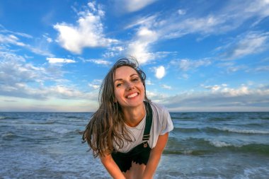 Rüzgarlı deniz kıyısındaki hoş genç bayan tatilin tadını çıkarıyor. Güzel kız gün batımından sonra mavi gökyüzü olan akşam deniz sahilinde dinleniyor.