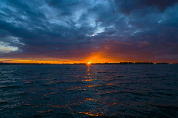 湖の上にカラフルな夕日 オレンジ色の日の出と劇的な曇りの空 — ストック写真
