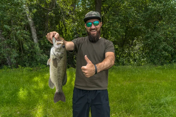Successful Bass Fishing Smiling Bearded Fisherman Sunglasses Bass Fish Show — Foto de Stock