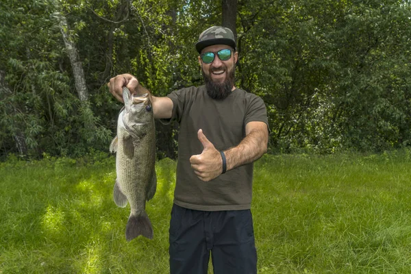 Successful Bass Fishing Smiling Bearded Fisherman Sunglasses Bass Fish Show — Φωτογραφία Αρχείου