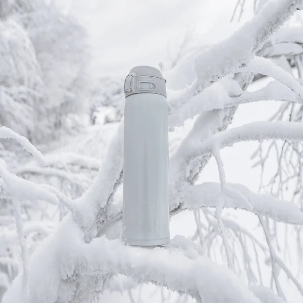 冬季休闲活动用的白色保温瓶 冬景背景下 雪地覆盖的树上的酒瓶保温瓶 — 图库照片