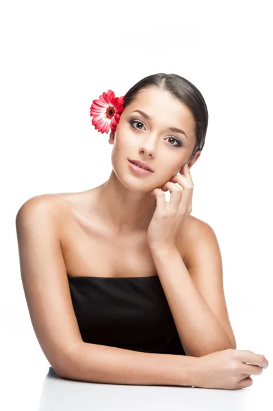 Young brunette female with gerbrera flower in hair — Stock Photo, Image