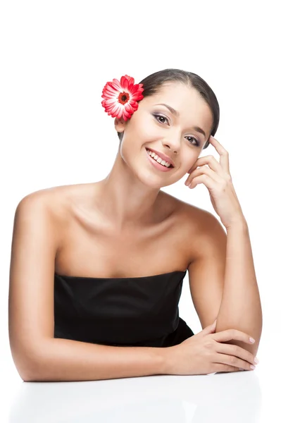 Jeune femme brune souriante avec fleur de gerbrera — Photo