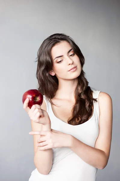 Thoughtfull young casual caucasian girl with red apple — Stock Photo, Image