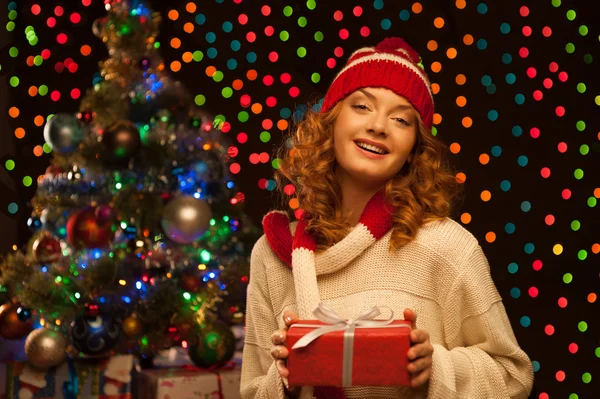 Молода усміхнена жінка тримає червоний різдвяний подарунок — стокове фото