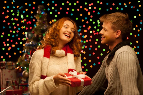 Junges glückliches lächelndes Paar macht ein Geschenk — Stockfoto