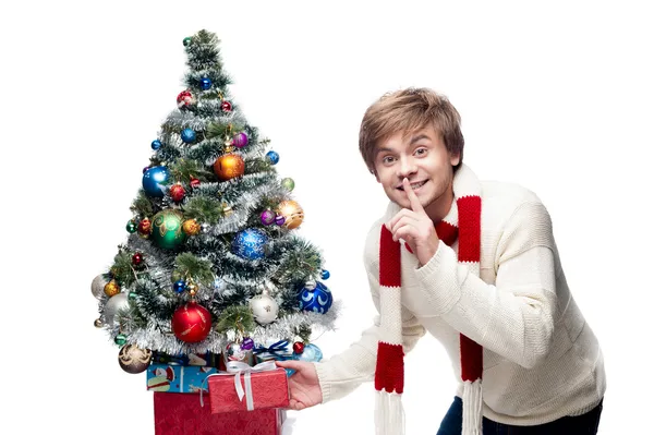 Genç gülümseyen adam Hediyelik Noel ağacının altına koyar — Stok fotoğraf