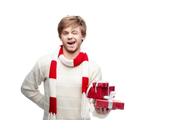 Young winking man holding christmas gifts — Stock Photo, Image