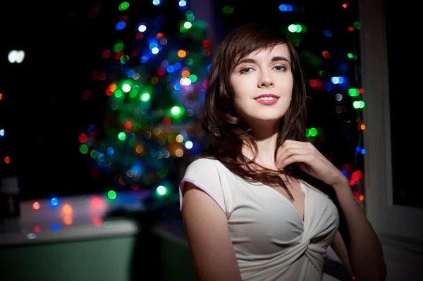 Smiling woman and christmas tree on background — Stock Photo, Image