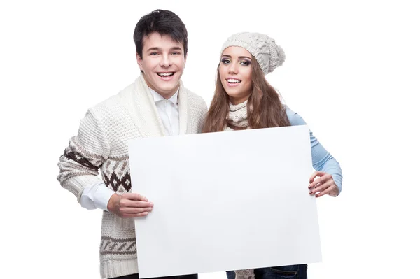 Unga leende vintern par med stor skyltνέοι που είναι χαμογελώντας ζευγάρι χειμώνα που κατέχουν μεγάλη πινακίδα — Φωτογραφία Αρχείου