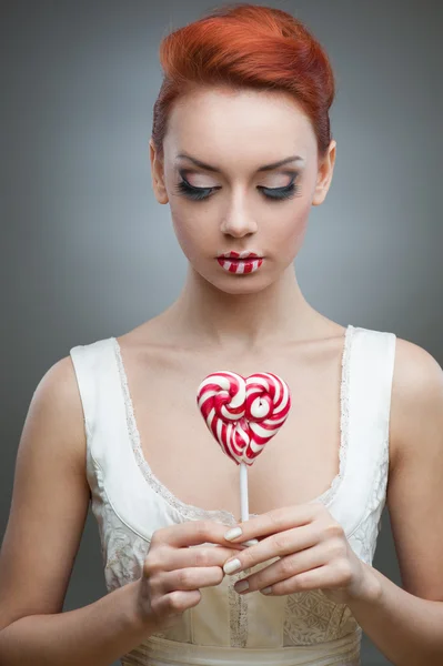 Рыжая девушка держит конфеты — стоковое фото