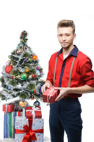 Mladý ročník muž drží dárek u vánočního stromu — Stock fotografie