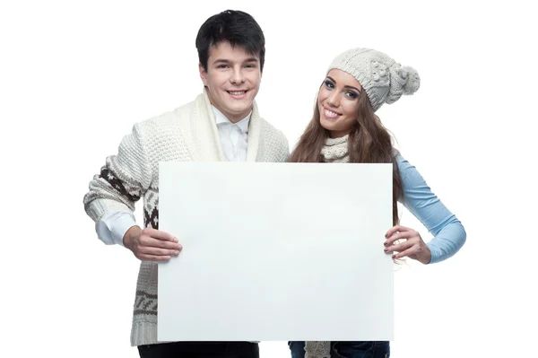 Jovem sorrindo casal de inverno segurando grande sinal — Fotografia de Stock