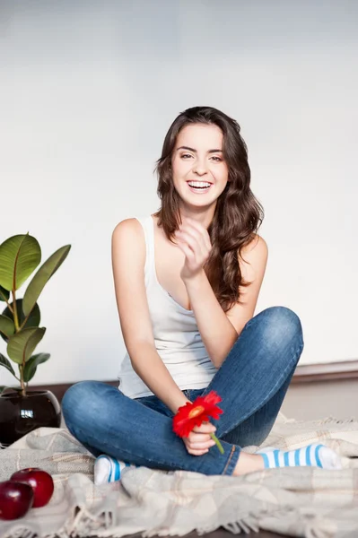 Sorridente ragazza bruna casuale che tiene il fiore rosso — Foto Stock