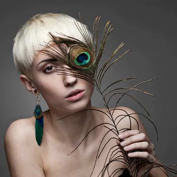 Attractive blond woman holding peacock feather — Stock Photo, Image