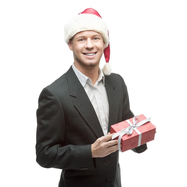 Cheerful businessman in santa hat holding red gift — Stock Photo, Image