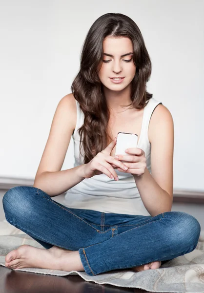 Jovem mulher sentada com telefone celular — Fotografia de Stock