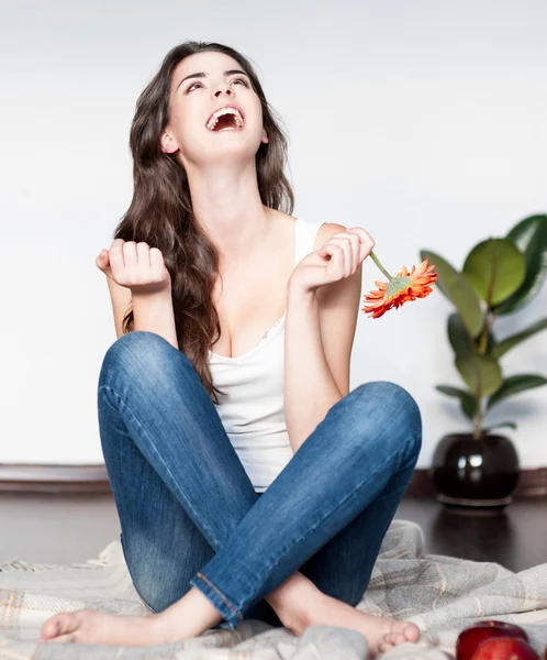 Emotional young woman sitting with red flower — Stock Photo, Image