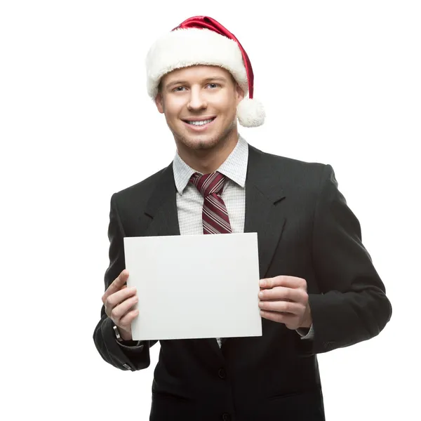 Young smiling businessman in santa hat holding sign — Stock Photo, Image