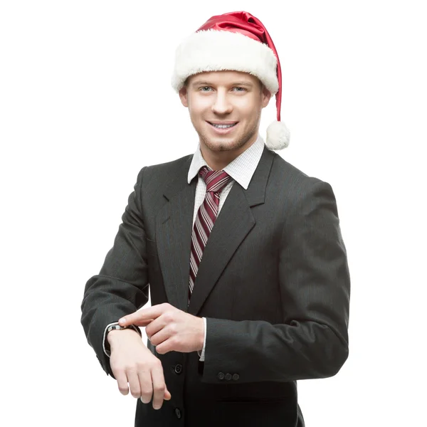 Young smiling businessman in santa hat pointing at watch — Stock Photo, Image