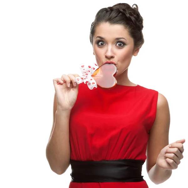 Caucasian woman in red dress licking lollipop — Stock Photo, Image