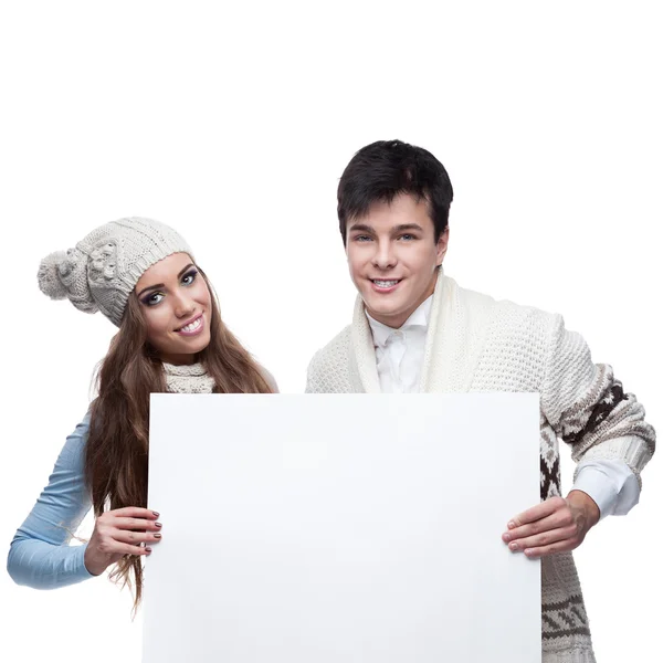 Unga leende vintern par med stor skyltνέοι που είναι χαμογελώντας ζευγάρι χειμώνα που κατέχουν μεγάλη πινακίδα — Stockfoto