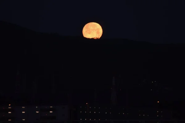 看到Moonset 黎明时分 山脊上满月的光反射在朦胧的水面上 — 图库照片