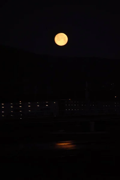 月明かりの光景 山の尾根に沈む満月の光は 夜明けに薄暗い川の表面に反映されます — ストック写真