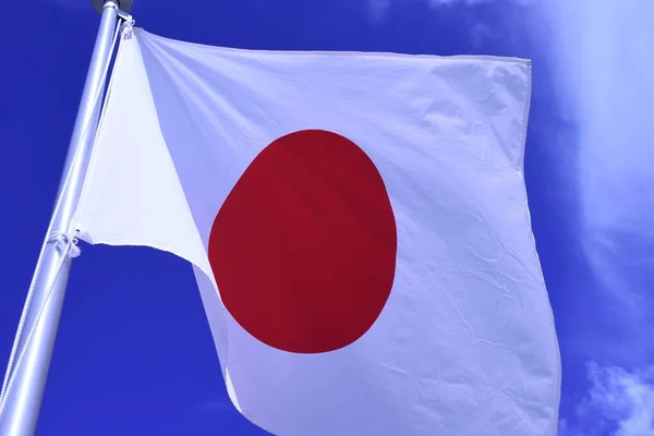 Japanese flag fluttering in the wind. In Japan, it is called \'Hinomaru\' and symbolizes the rising sun. Red and white are traditional Japanese colors and are considered auspicious.