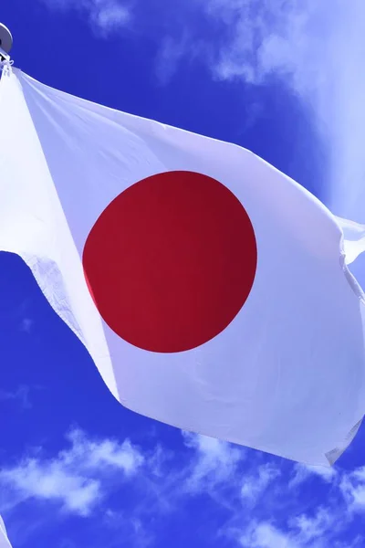 Japanese flag fluttering in the wind. In Japan, it is called 'Hinomaru' and symbolizes the rising sun. Red and white are traditional Japanese colors and are considered auspicious.