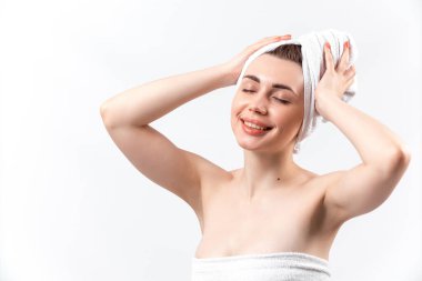 Beyaz havluyla güzel esmer kız beyaz arka planda duruyor.